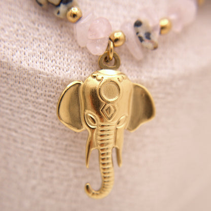 Gold elephant pendant on a beaded necklace against a neutral background