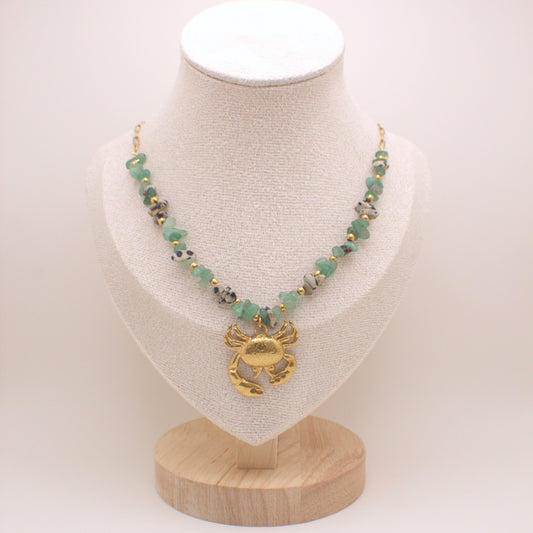 Necklace with green beads and gold crab pendant on a white mannequin bust.