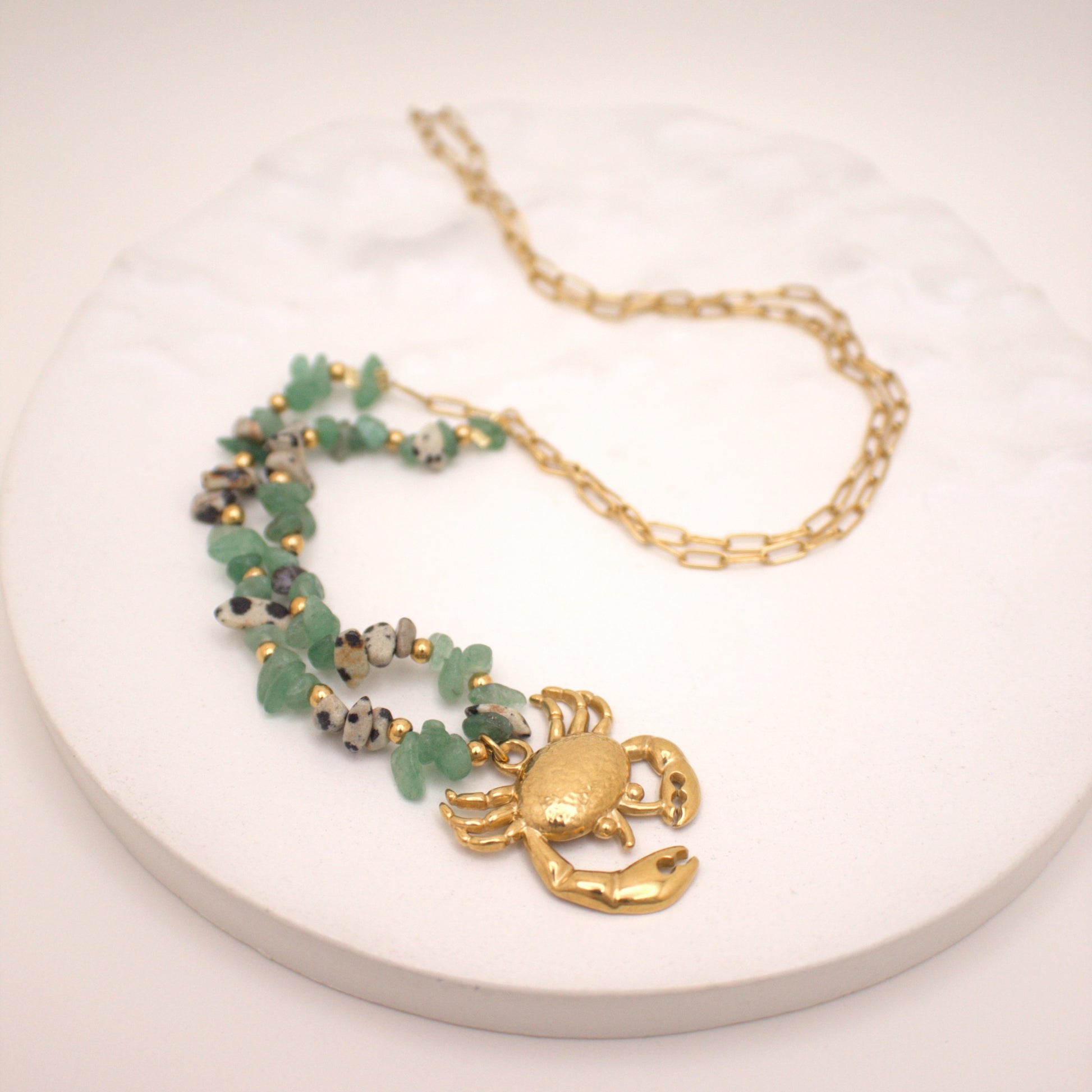 Necklace with a gold crab pendant on a white surface