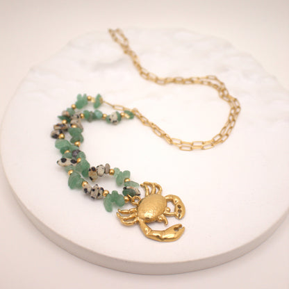 Necklace with a gold crab pendant on a white surface