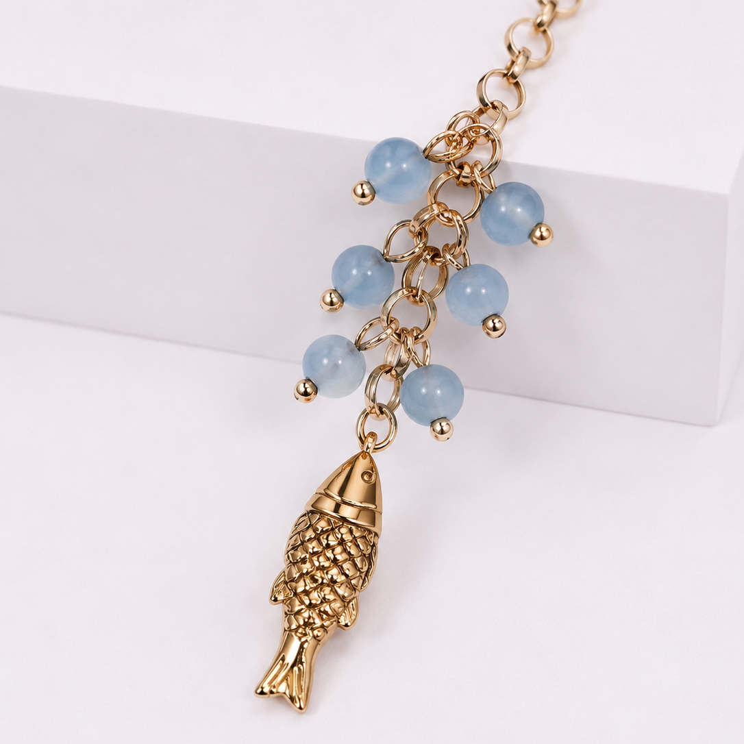 Gold-tone fish charm necklace with light blue bead accents, displayed on a clean white background.