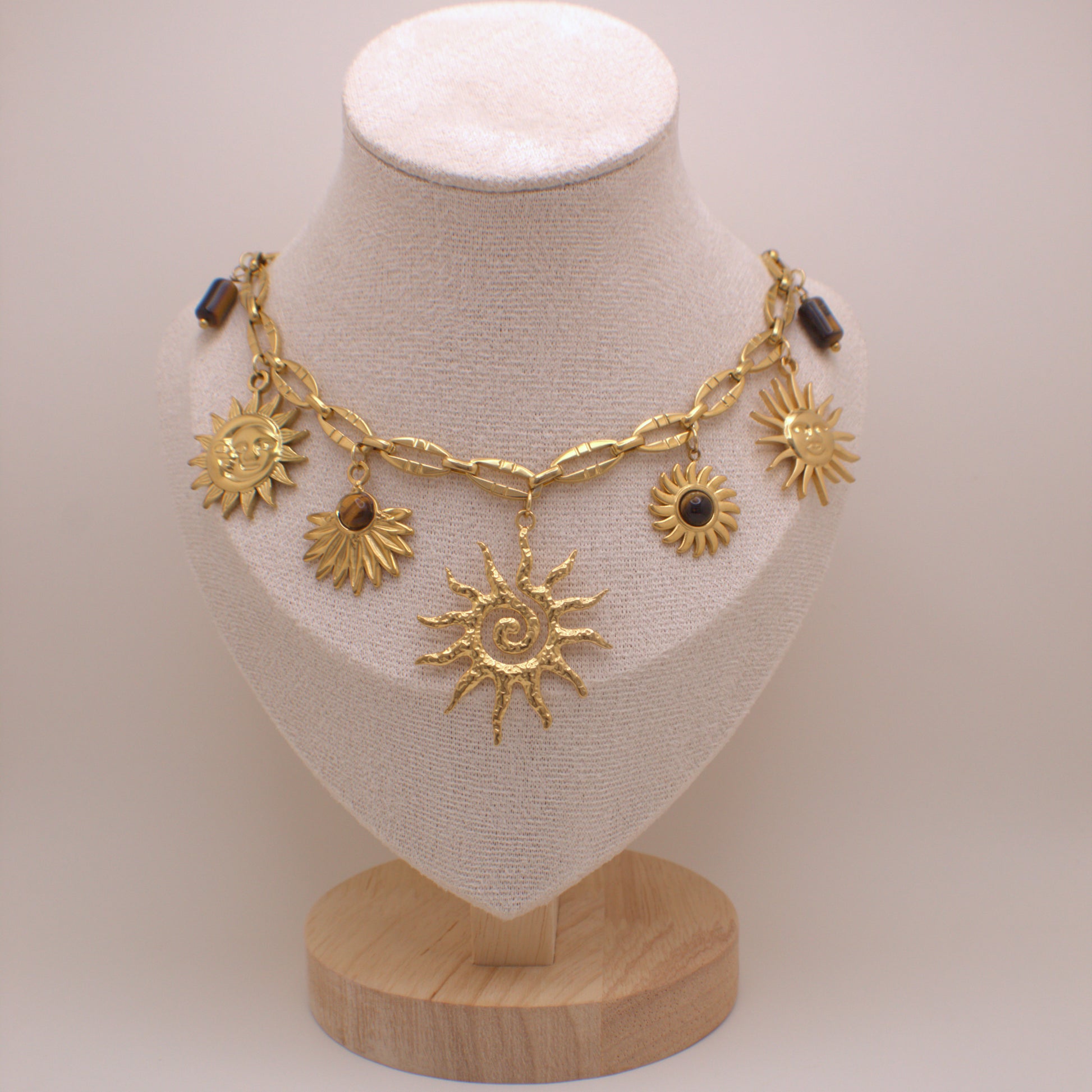 Gold necklace with sun designs on a mannequin bust against a plain background