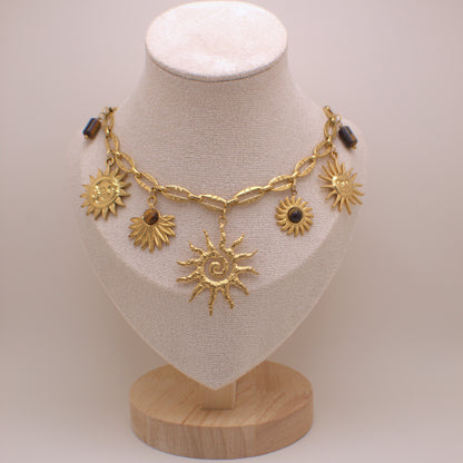 Gold necklace with sun designs on a mannequin bust against a plain background