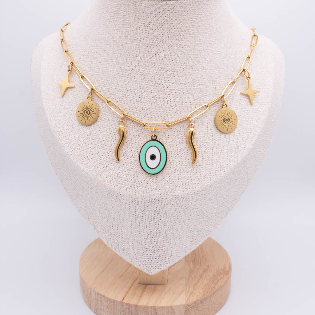 Gold chain necklace with multiple charms, including a central turquoise and white evil eye pendant, displayed on a beige fabric jewelry bust.