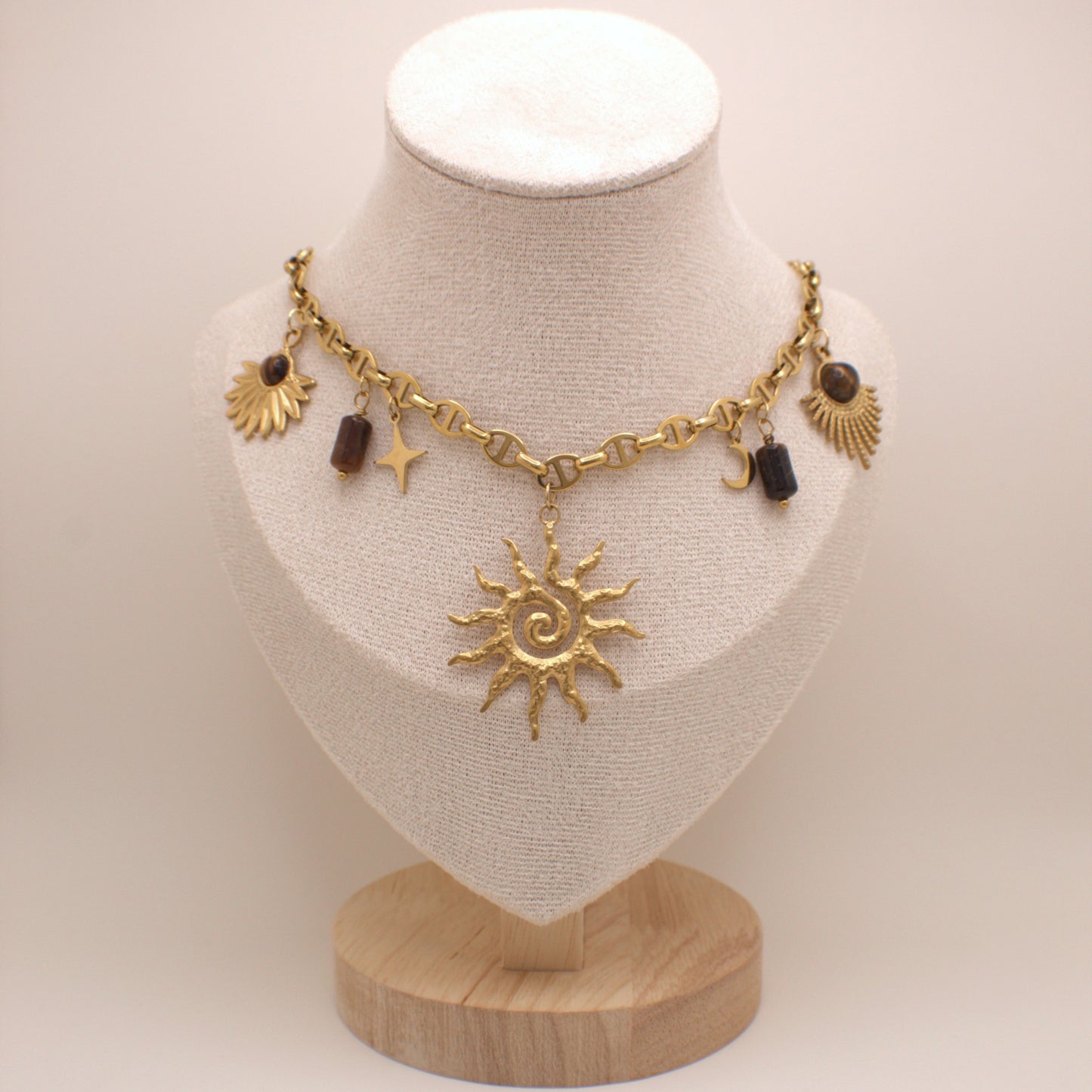 Gold necklace with sun pendant on a mannequin bust against a white background