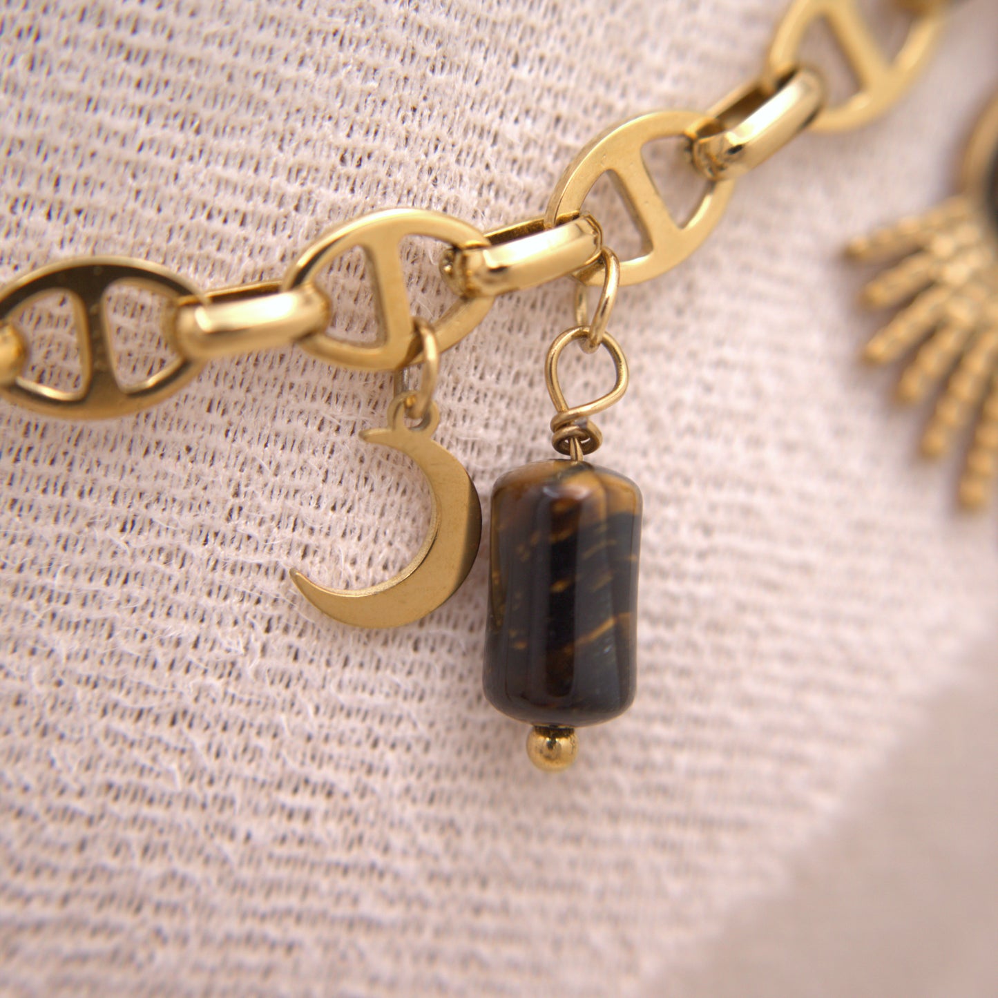 Gold bracelet with charms on a textured beige background
