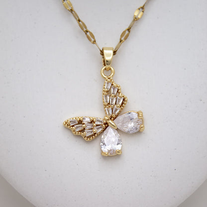 Gold butterfly-shaped pendant necklace on a light gray background