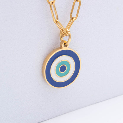 Gold chain necklace with a circular evil eye pendant featuring blue, white, and teal concentric circles on a light gray background.