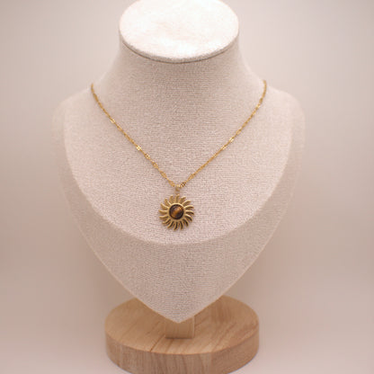 Gold necklace with a sunflower pendant on a mannequin bust against a white background