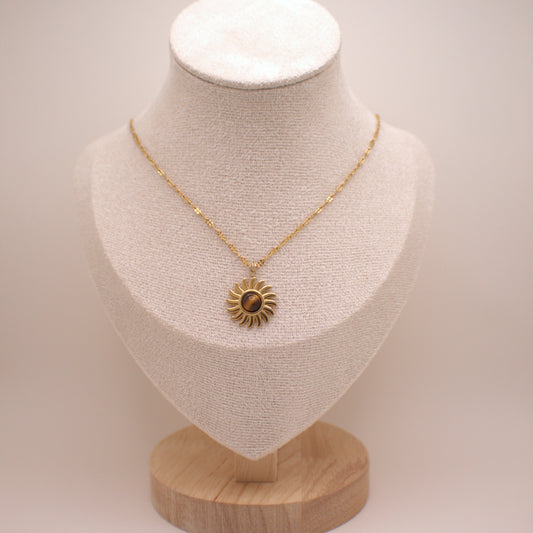 Gold necklace with a sunflower pendant on a mannequin bust against a white background