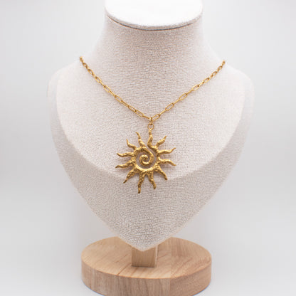 Gold sun-shaped pendant necklace on a mannequin bust with a white background