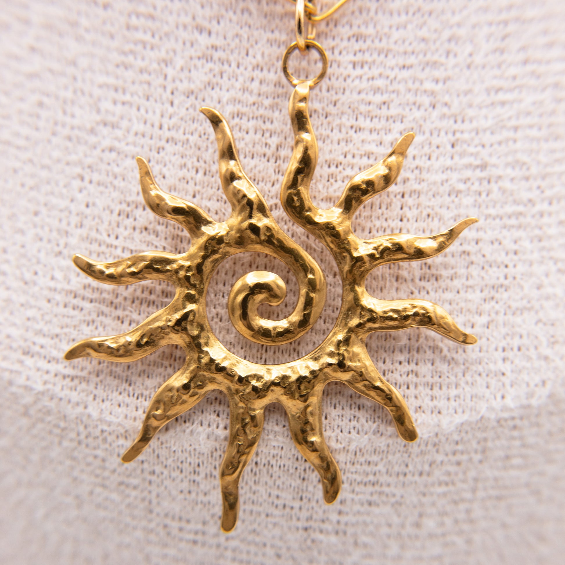 Gold sun-shaped pendant on a light fabric background