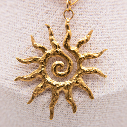 Gold sun-shaped pendant on a light fabric background