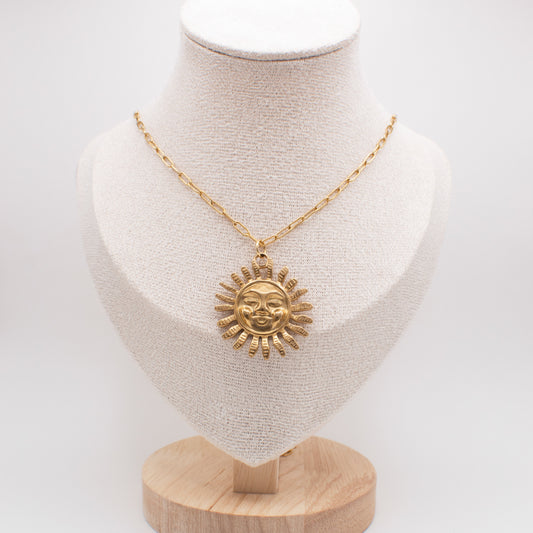 Gold necklace with sun pendant on a mannequin bust against a white background