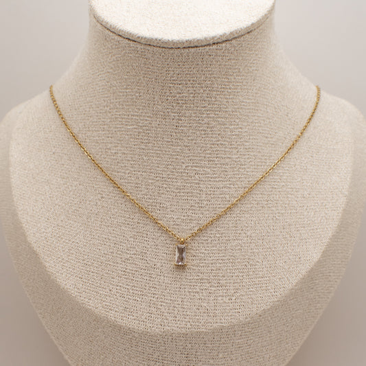 Gold necklace with a pendant on a mannequin bust against a neutral background