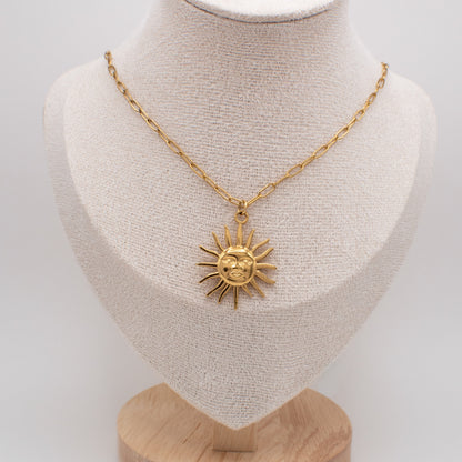 Gold necklace with a sun pendant on a mannequin bust against a white background