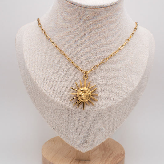 Gold necklace with a sun pendant on a mannequin bust against a white background