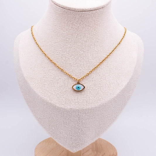 A gold chain necklace with an evil eye pendant displayed on a textured cream fabric jewelry bust against a white background.