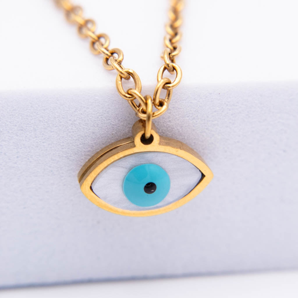 Gold-tone evil eye pendant necklace with a turquoise blue iris and black pupil, shown on a white display stand.