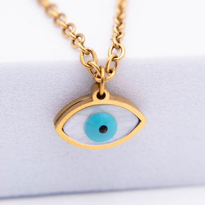 Gold-tone evil eye pendant necklace with a turquoise blue iris and black pupil, shown on a white display stand.