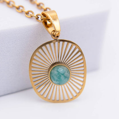 Gold sunburst pendant necklace with a round turquoise-blue stone in the center, shown on a white background.