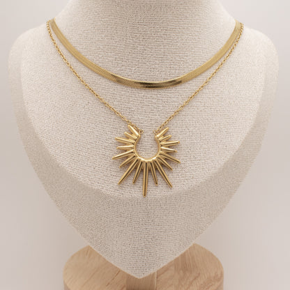 Gold necklace with a sunburst pendant on a mannequin bust.