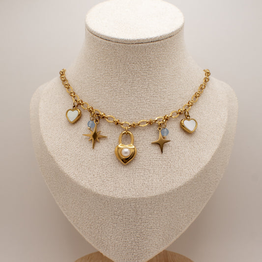 Gold necklace with charms on a mannequin bust against a neutral background