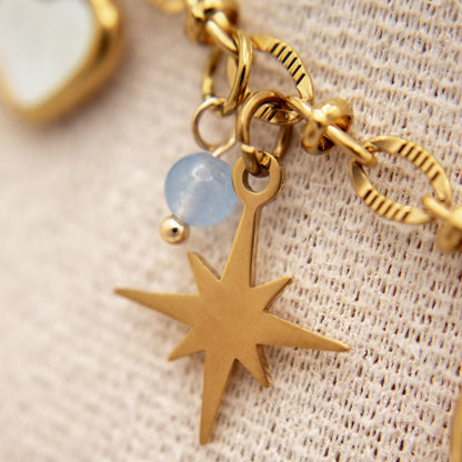 Gold bracelet with star charm and blue bead on textured fabric background
