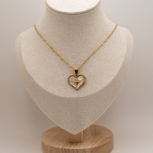 Gold necklace with a heart-shaped pendant on a mannequin bust.