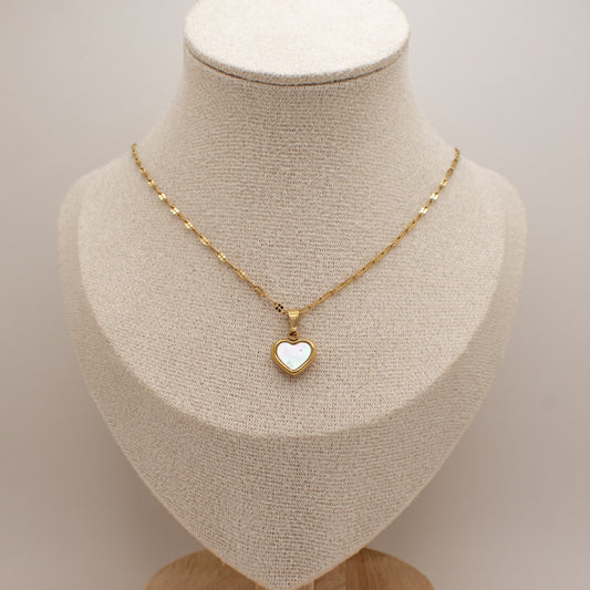 Gold necklace with a heart-shaped pendant on a mannequin bust.