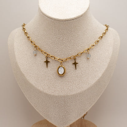 Gold necklace with star and oval pendant on a mannequin bust.