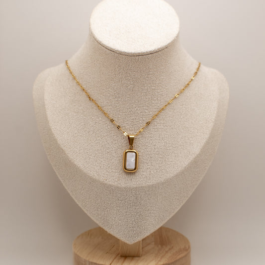 Gold necklace with a pendant on a mannequin bust against a neutral background