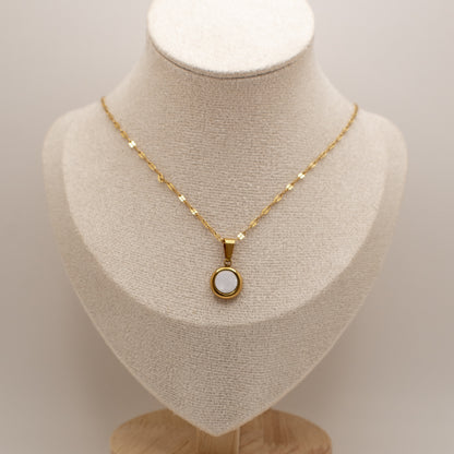 Gold necklace with a pendant on a mannequin bust against a neutral background