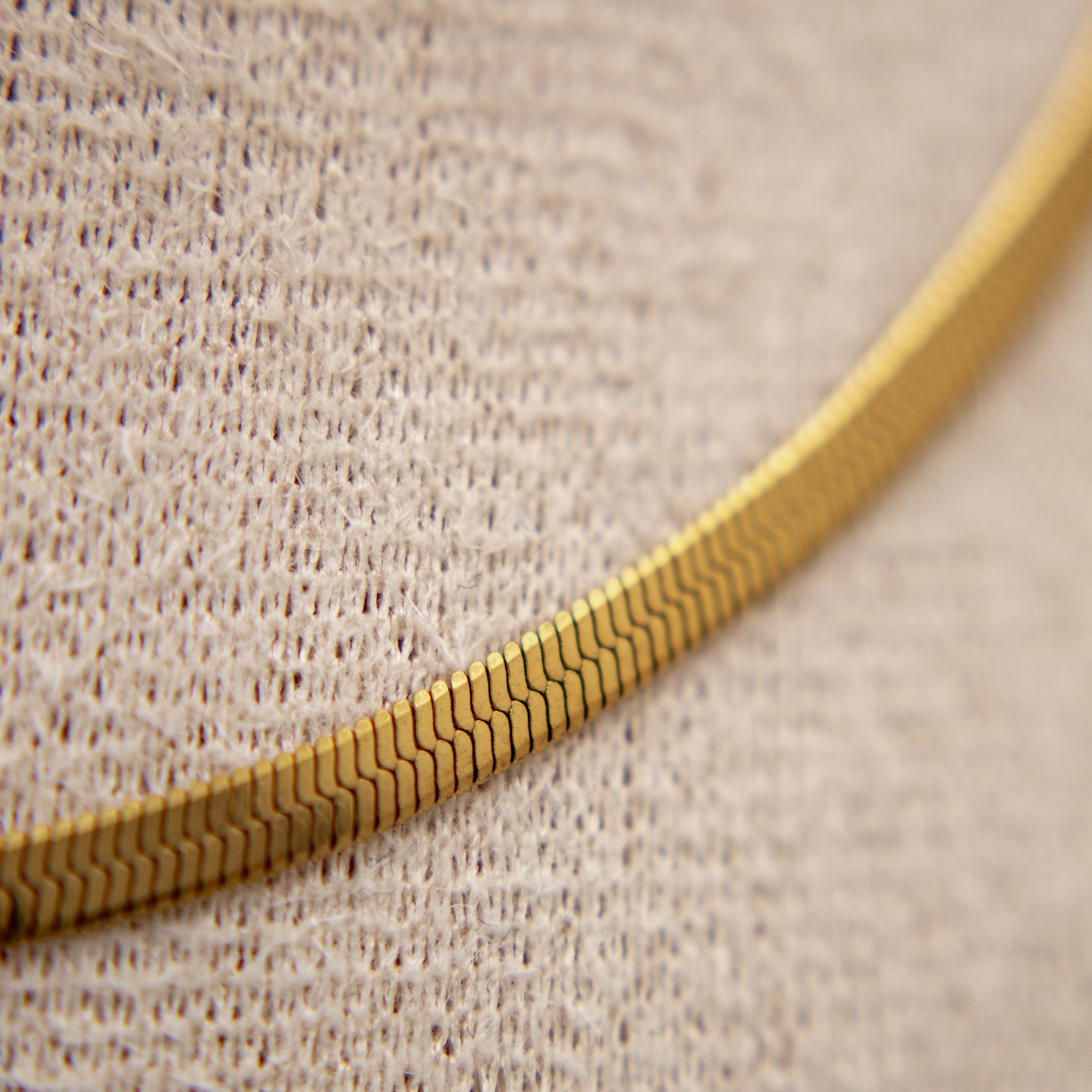 Gold chain on a textured beige background