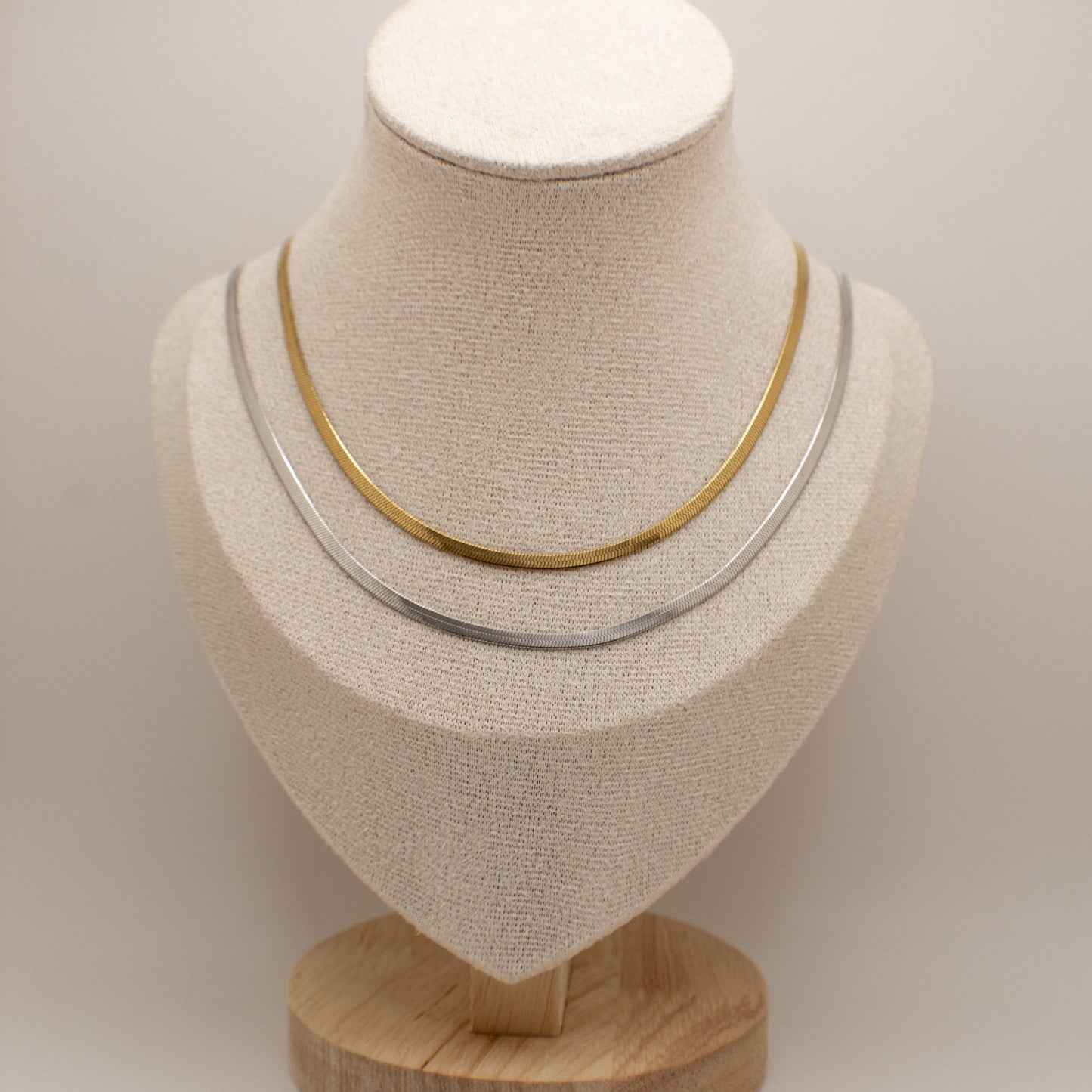 Two necklaces on a mannequin bust against a plain background