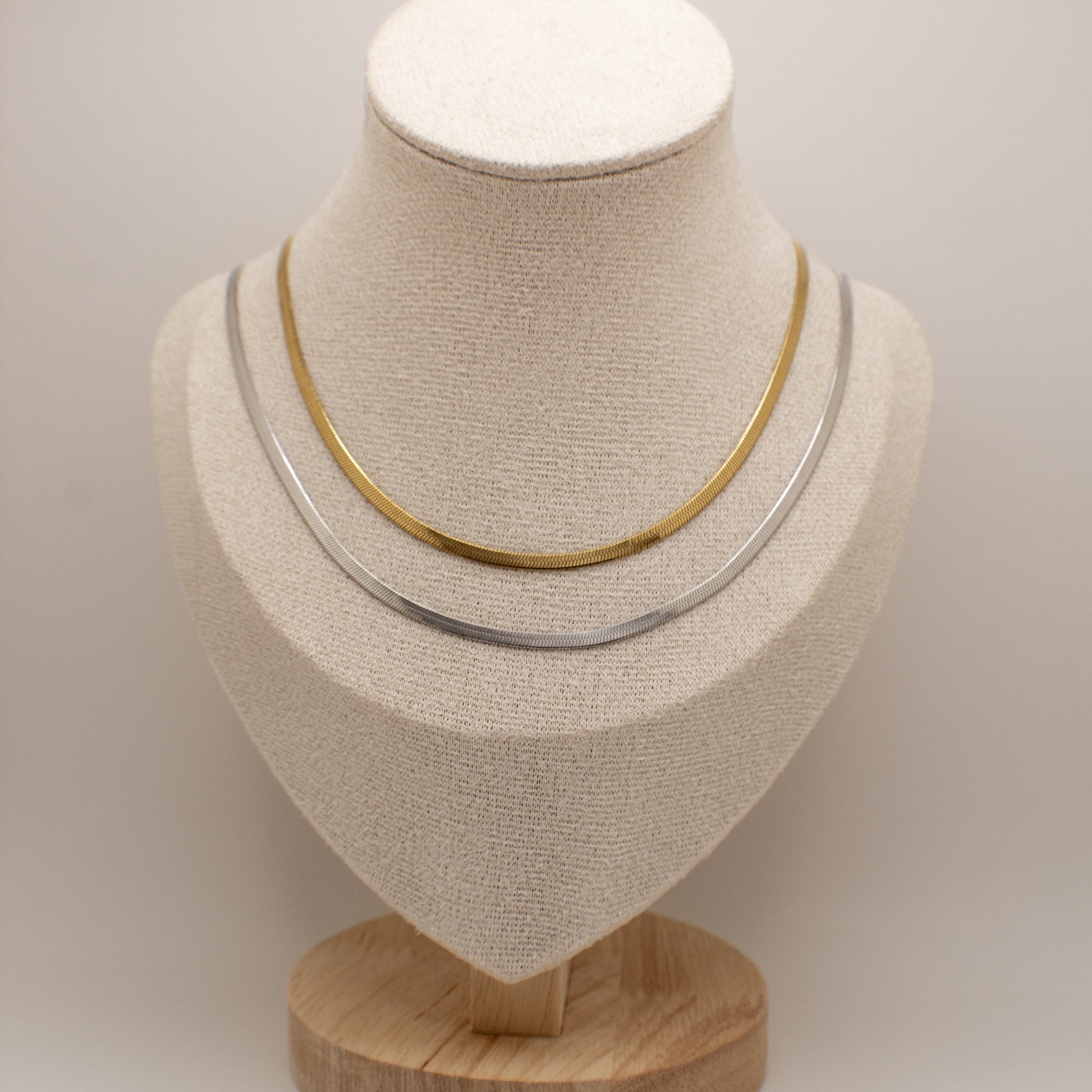 Two necklaces on a mannequin bust against a plain background
