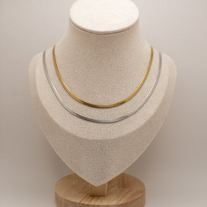 Two necklaces on a mannequin bust against a plain background