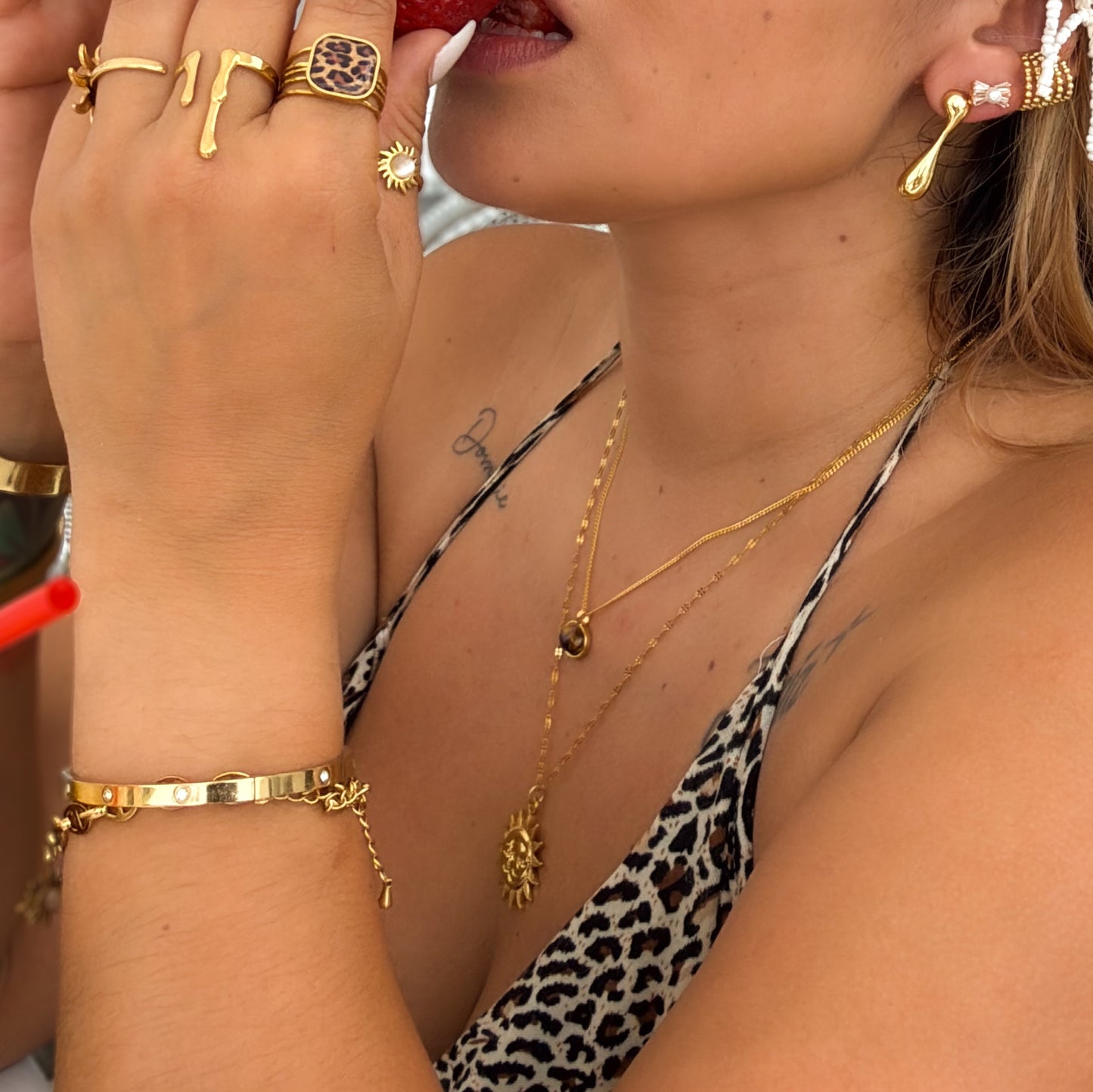 Close-up of a person wearing gold jewelry including rings, bracelets, and necklaces.