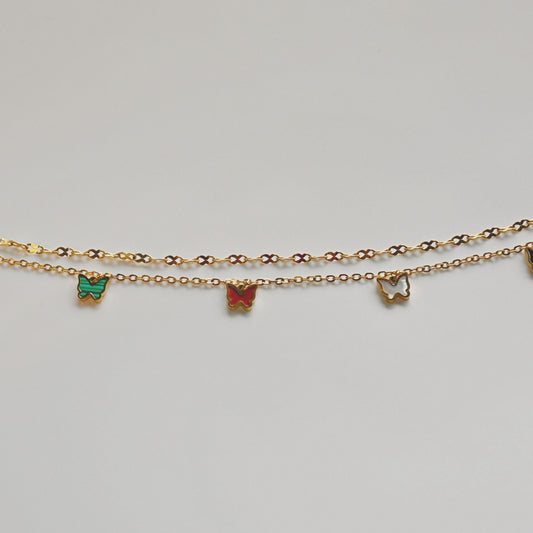 Gold anklet with colorful butterfly charms on a light gray background