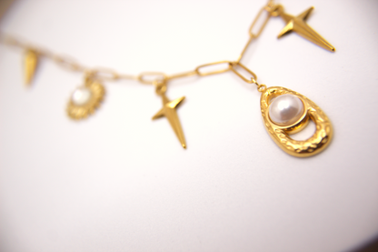 Gold charm necklace with stainless steel chain, pearl and sun details.