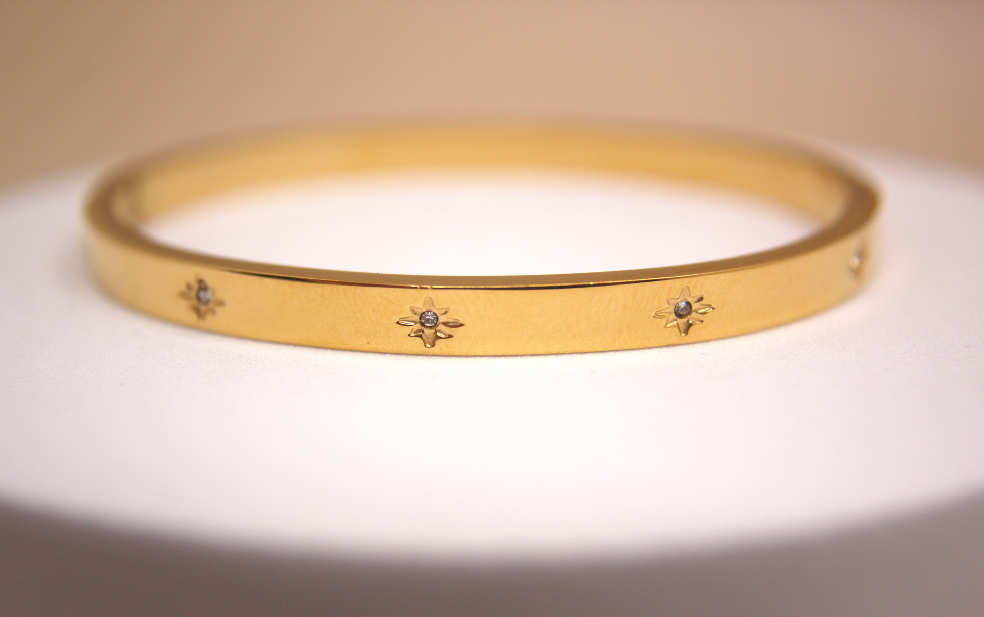 Gold and silver stainless steel bracelets with star engravings and cubic zirconia.