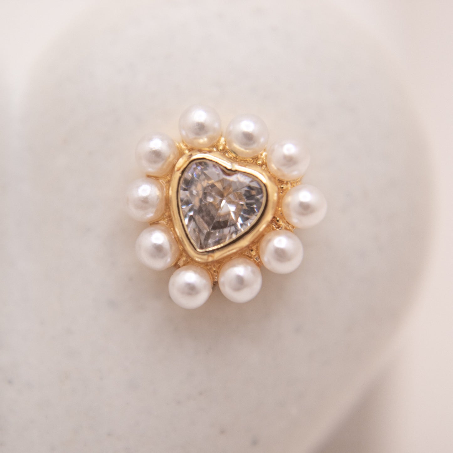 Heart-shaped gold studs featuring clear crystal and pearl details.
