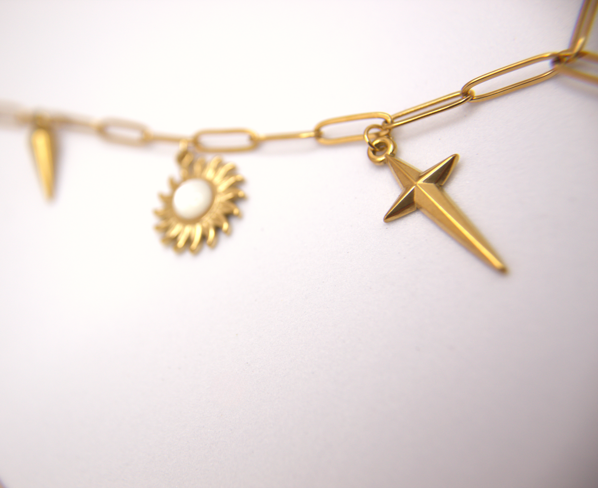 Trendy multicharm necklace with bold gold pendants and link chain.