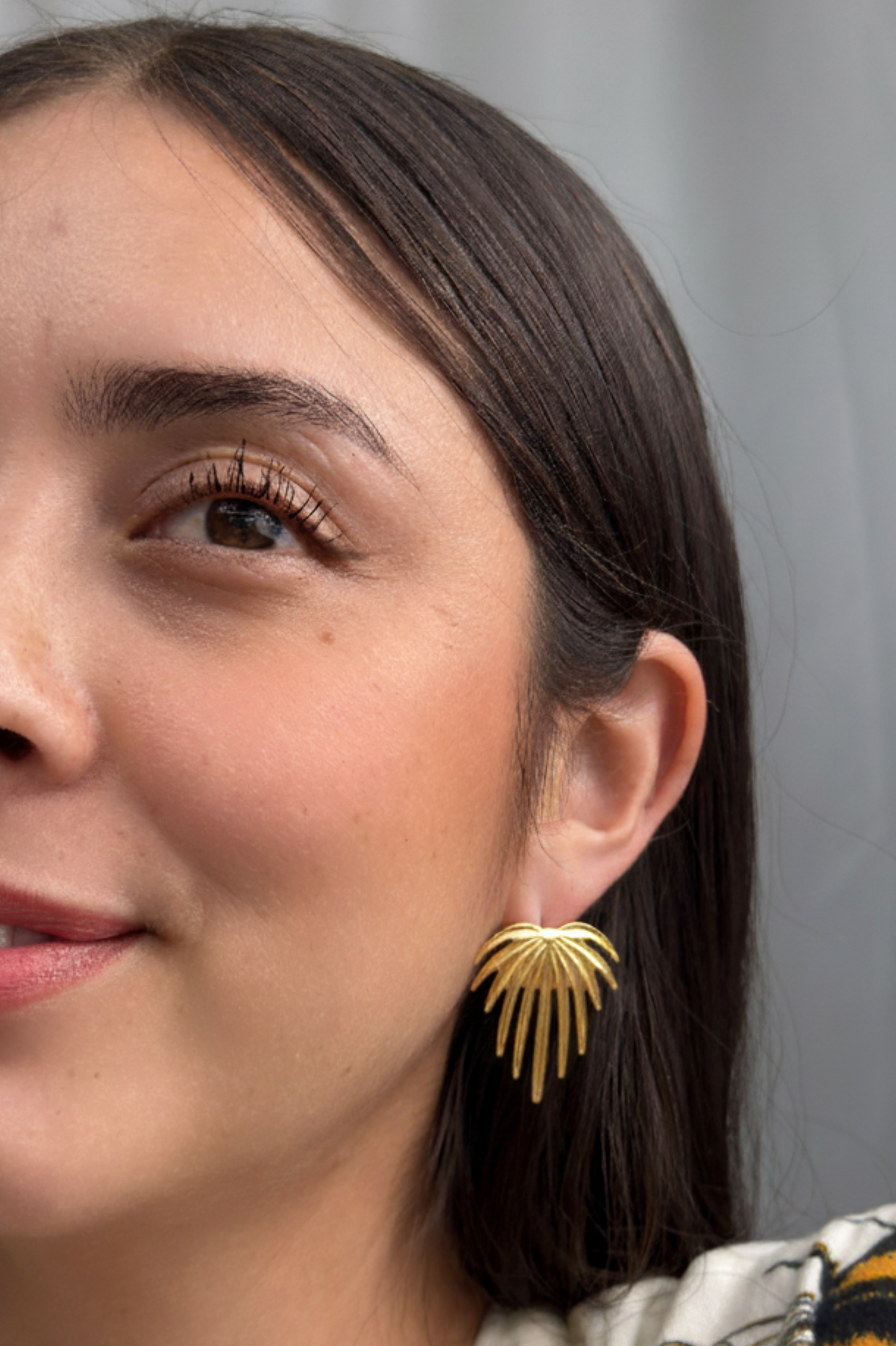 Large golden statement earrings inspired by palm leaves.