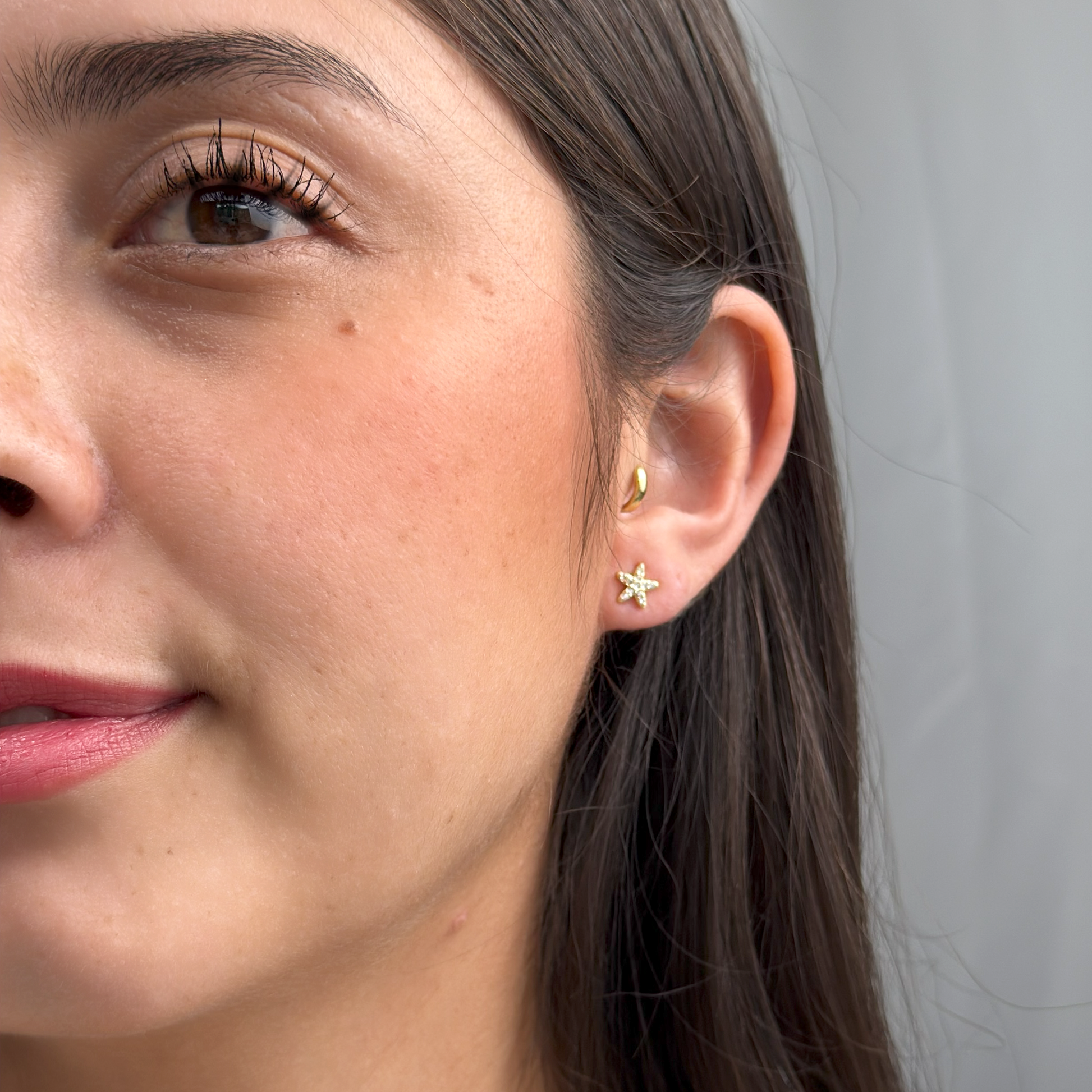 Ocean-inspired gold starfish studs with white cubic zirconia stones.