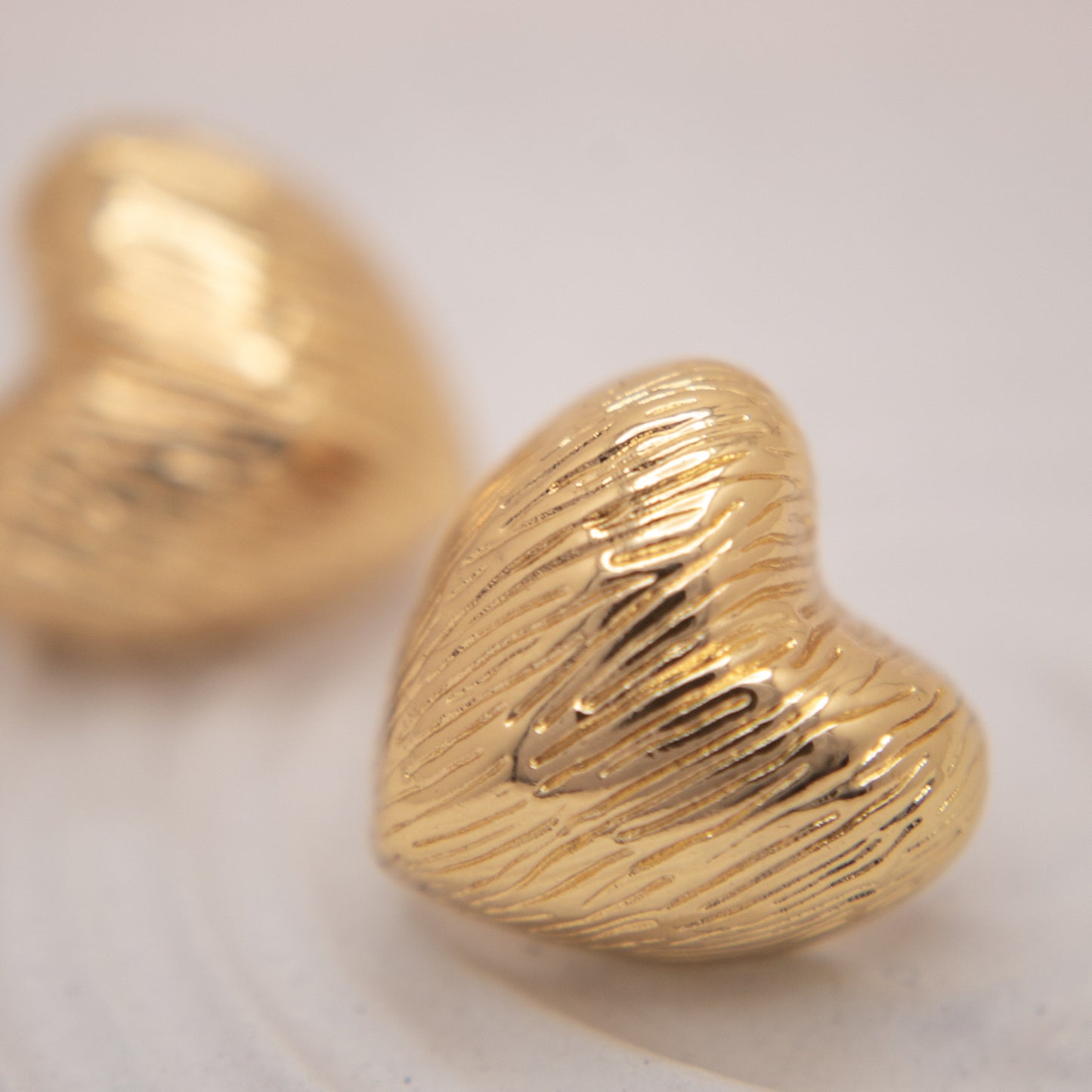 Gold textured heart stud earrings with organic finish