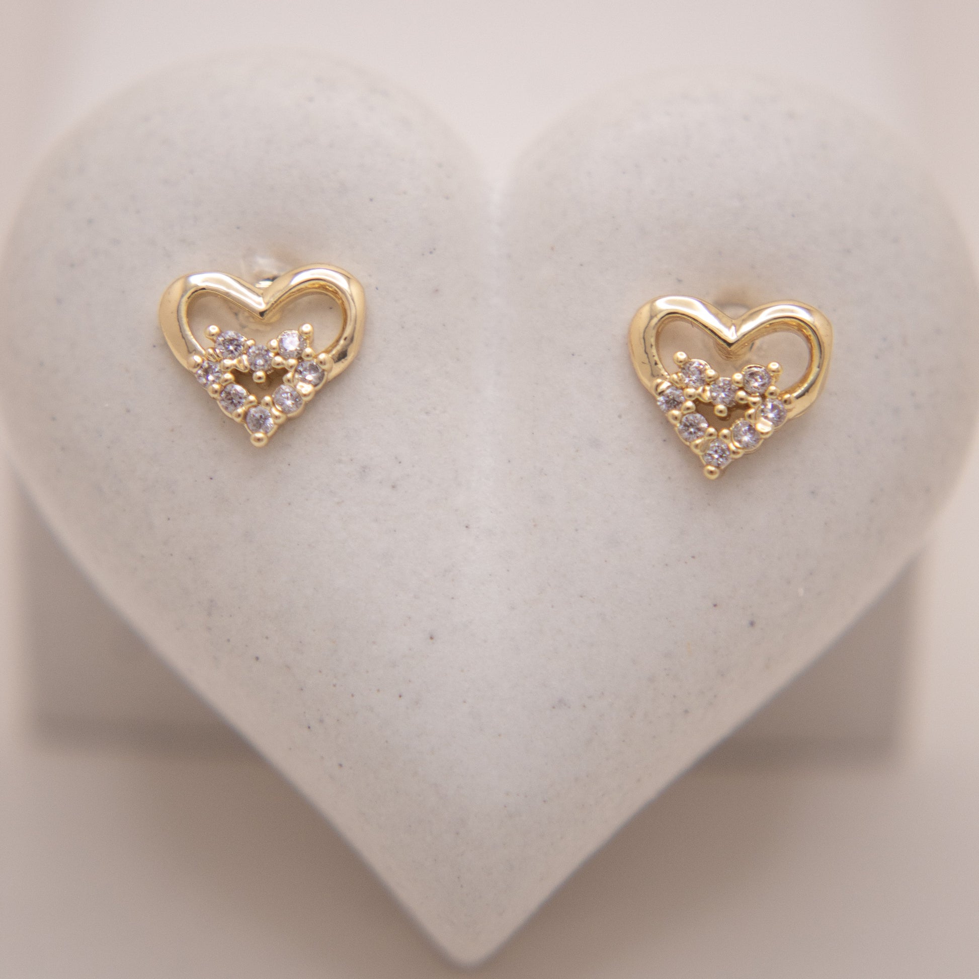 Minimal gold heart studs with sparkling zirconia details.