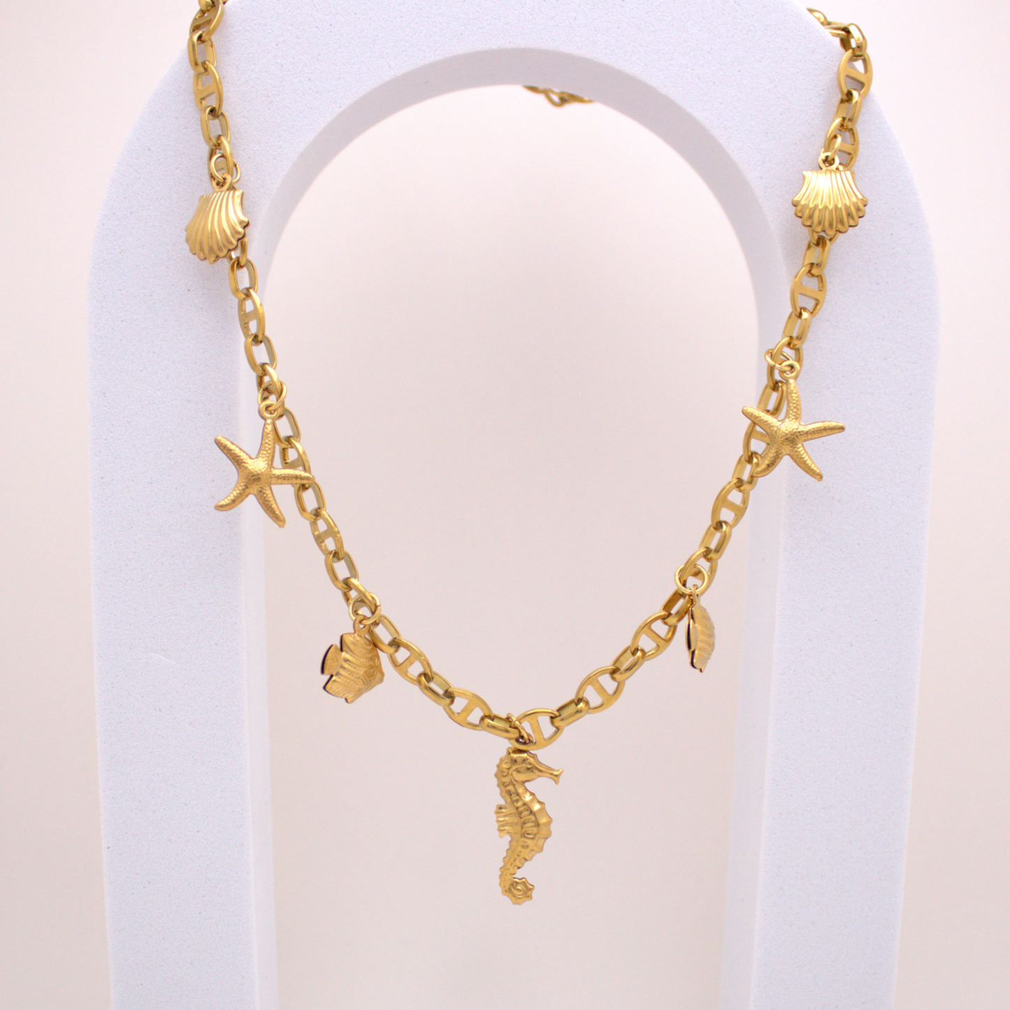 Gold necklace with seahorse, shell, and starfish charms by Selva&Co