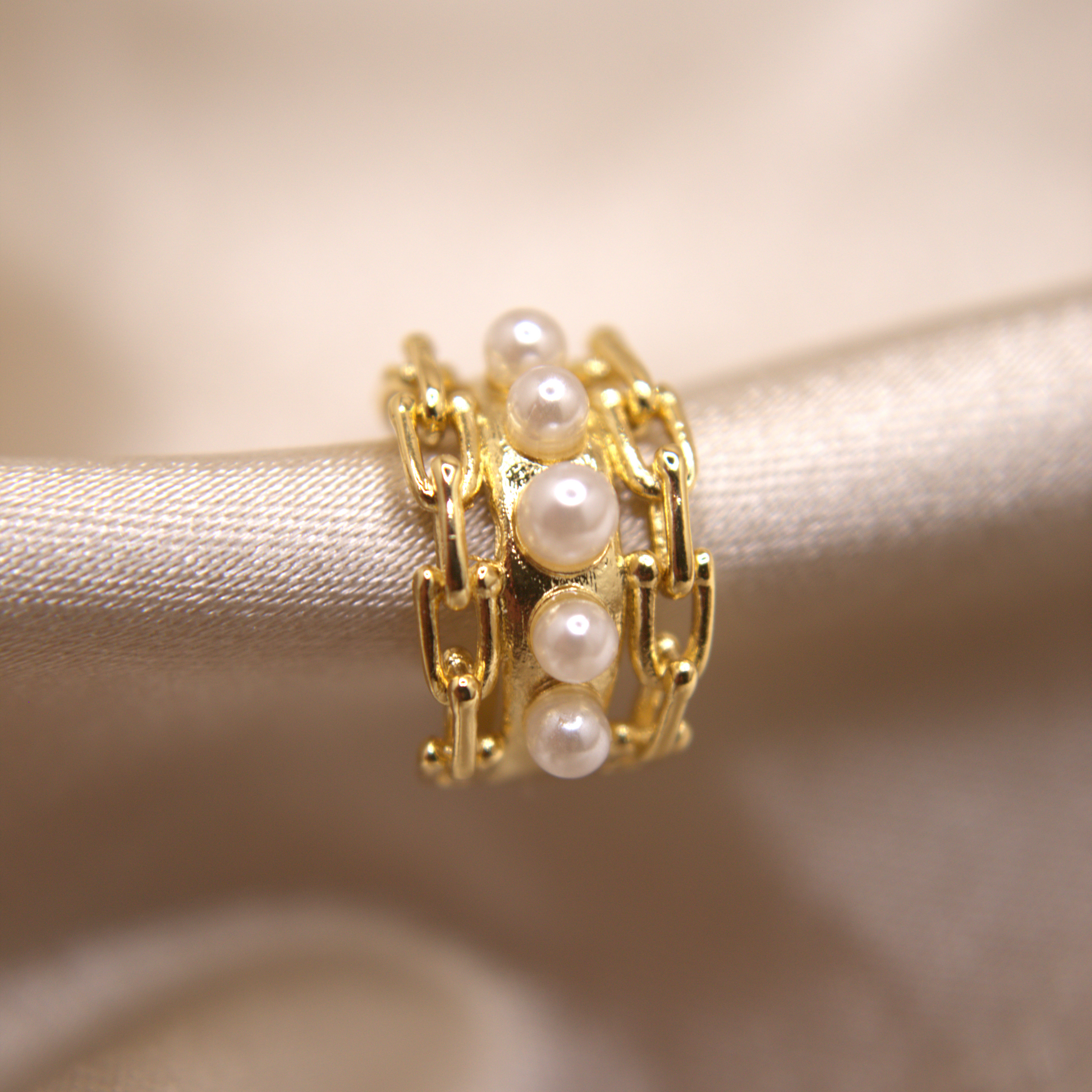 Dual-tone ear cuff with flowing structure and pearl embellishments.