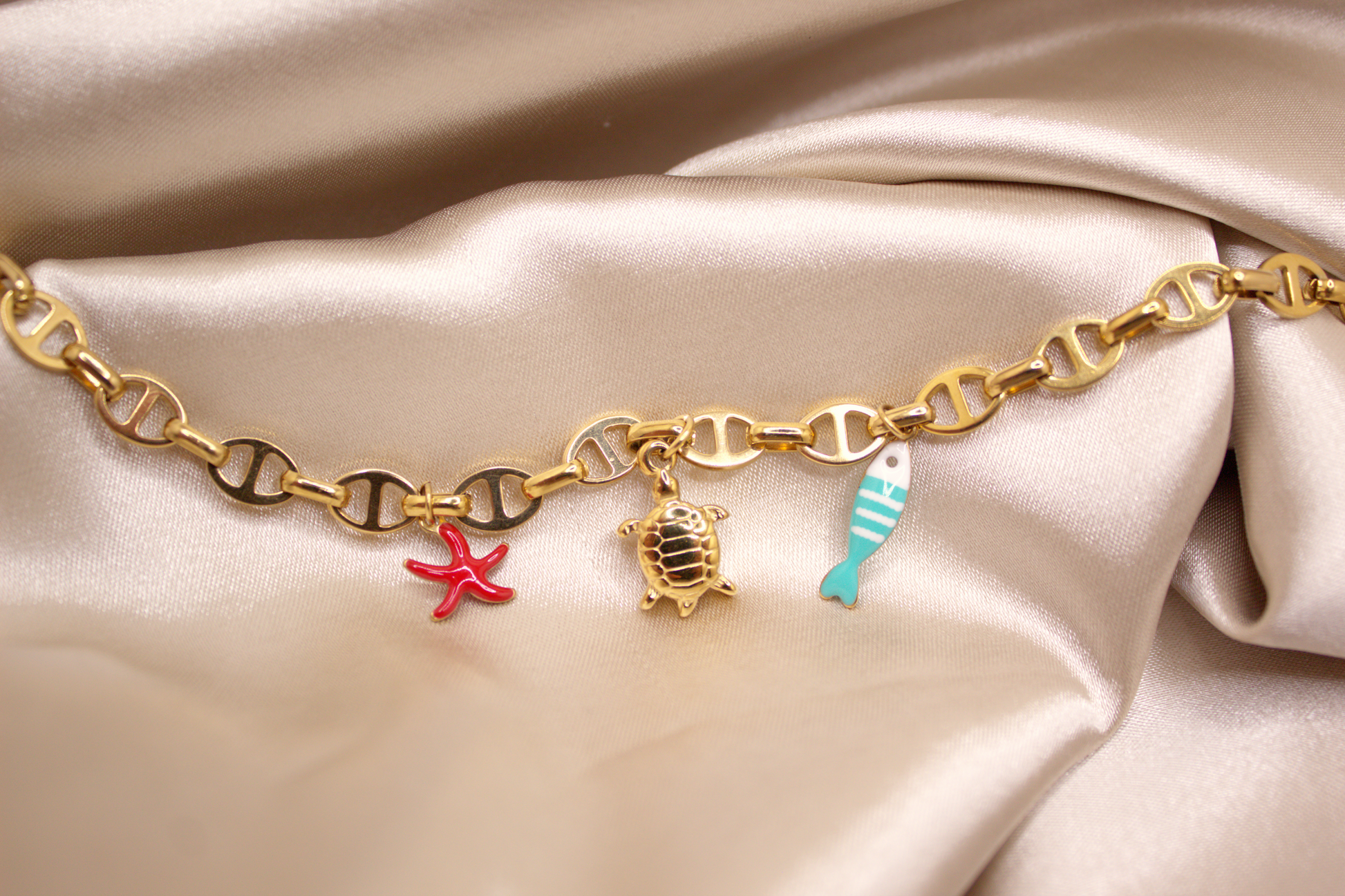 Ocean Voyage Bracelet in gold with turtle, red starfish, and blue fish charms